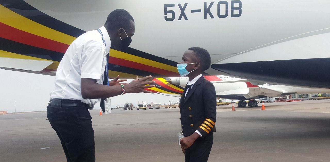 Ugandan "Captain" Graham Shema, 7, listens to his flight instructor, Simon Wadagu Bruno, about functions of some parts of a Bombardier CRJ900 aircraft at the Entebbe International Airport, in Entebbe. Credit: Reuters Photo