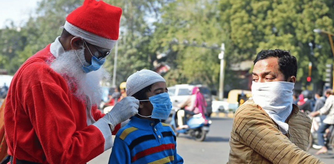 A social worker dressed as Santa Claus distributes facemasks to commuters as part of an awareness campaign against the Covid-19 coronavirus at a traffic junction in Ahmedabad on December 18, 2020. Credit: AFP Photo