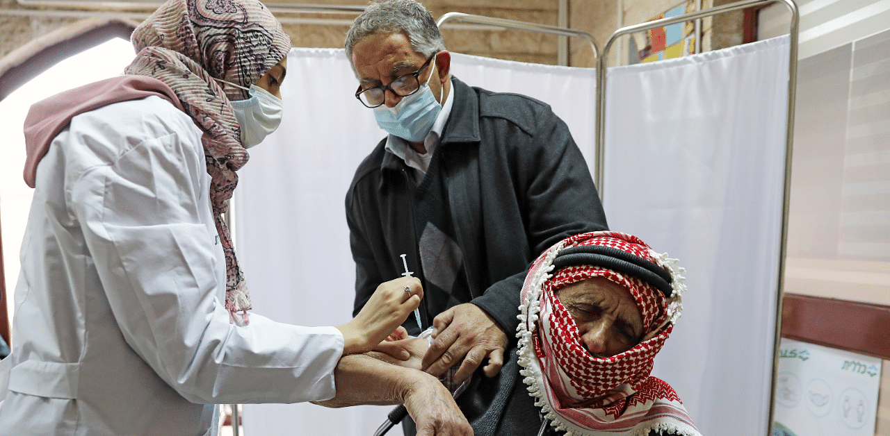 A Palestinian man is helped by his son as he receives a coronavirus vaccine in East Jerusalem. Credit: Reuters