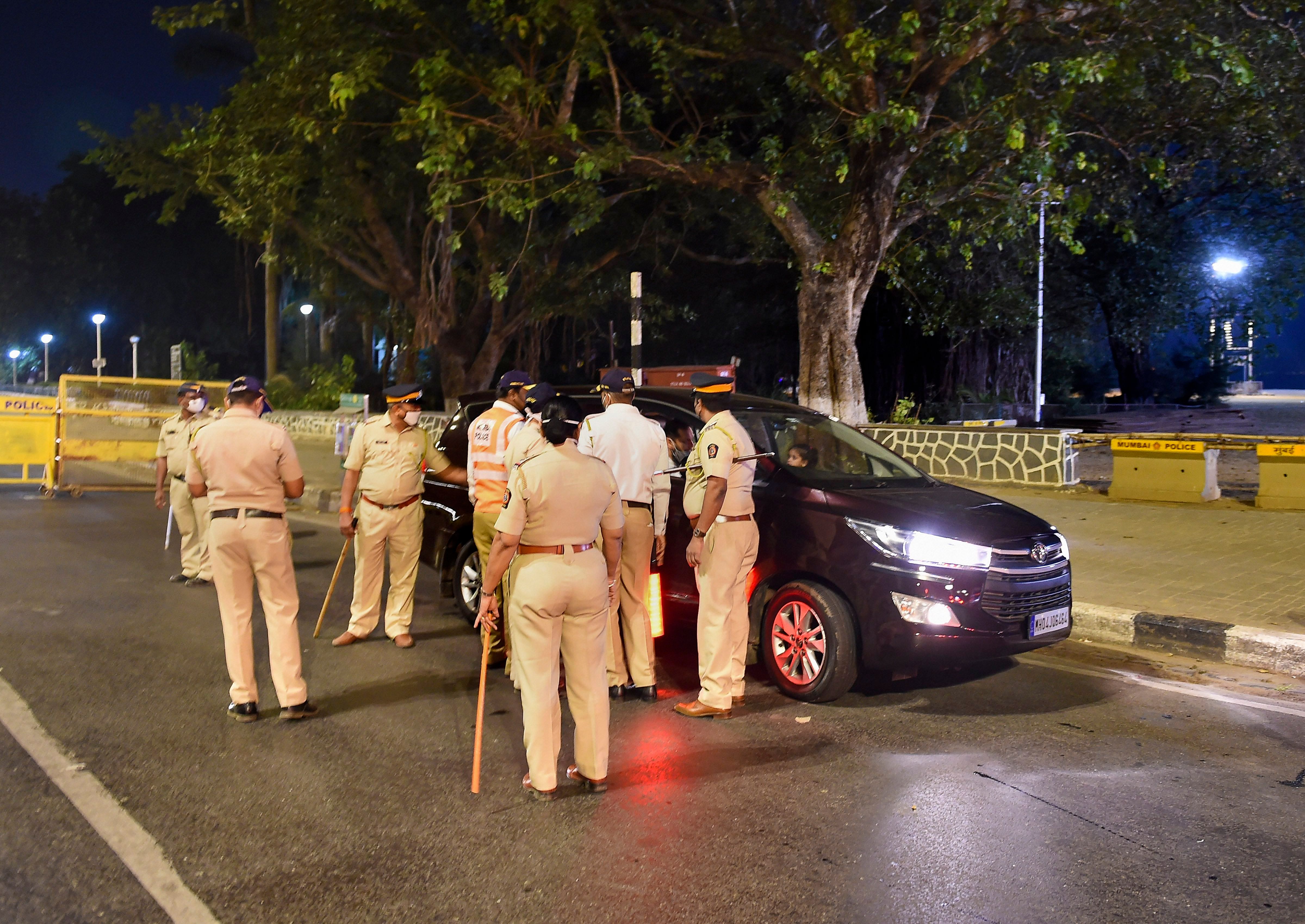 Police officers stop commuters at Girgaum Chowpatty during the night curfew in Mumbai. Credit: PTI Photo