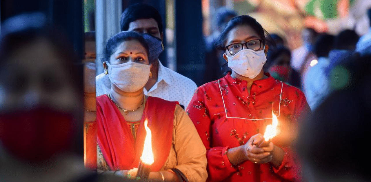 Devotees holding candles offer prayers at St Mary's Basilica on the occasion of Christmas festival, in Bengaluru, Friday, Dec. 25, 2020. Credit: PTI Photo