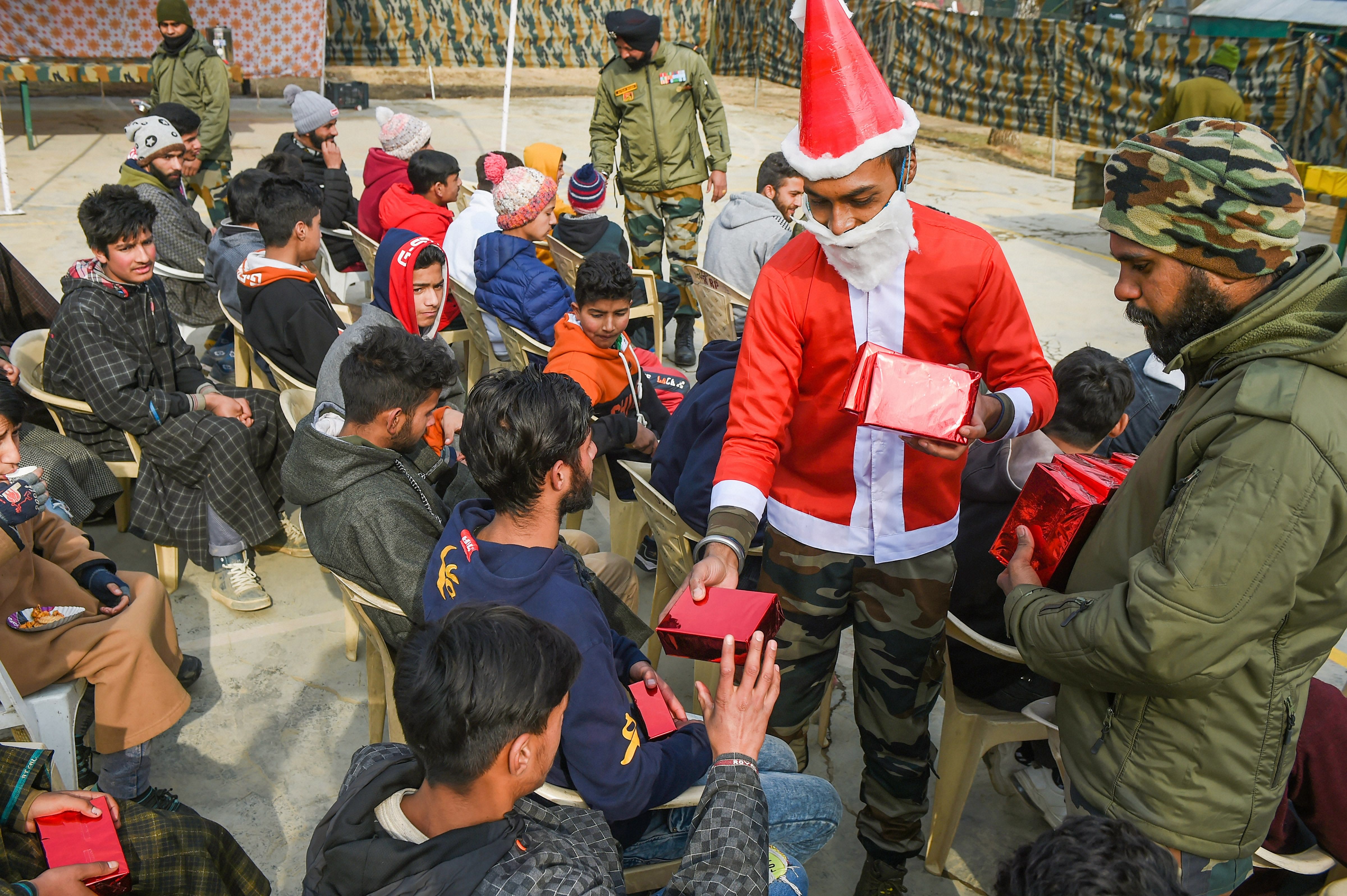 An army personnel dressed as Santa Claus distributes sweets among local youth during Christmas celebrations at Army Camp Larkipora in Anantnag district of south Kashmir, Friday, Dec. 25, 2020. Credit: PTI Photo