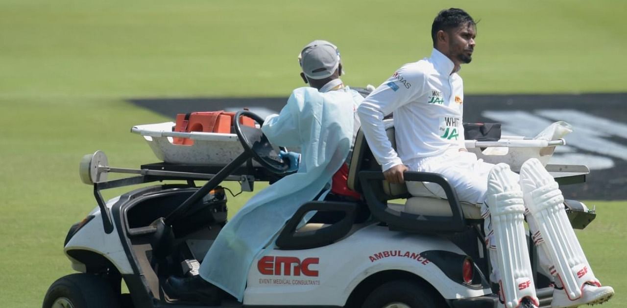 Sri Lanka's Dhananjaya de Silva (R) is helped off the field by medical staff after being injured during the first day of the first Test cricket match between South Africa and Sri Lanka at SuperSport Park in Centurion. Credit: AFP.
