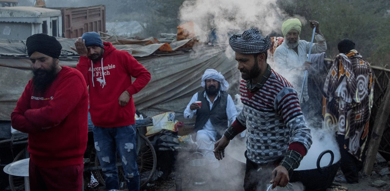 Farmers cook food on a cold winter morning at the site of a protest against new farm laws, at Singhu border, near New Delhi. Credit: Reuters File Photo