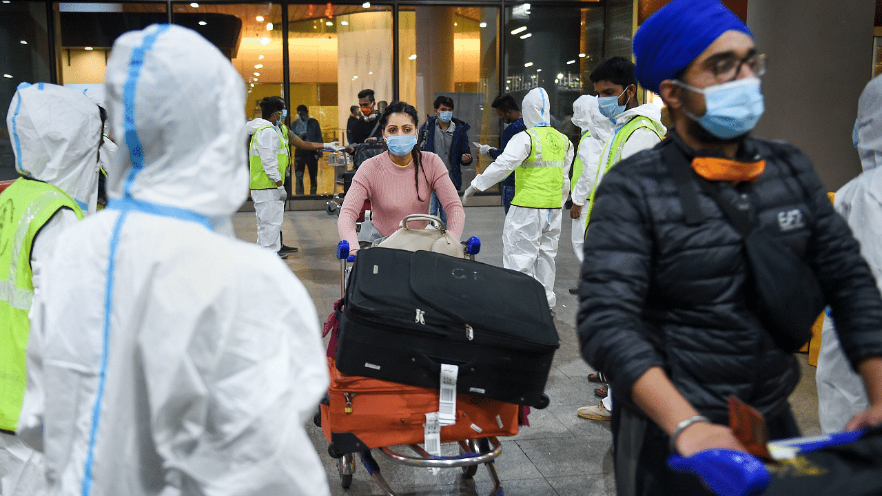 Municipal workers in personal protective equipment look on as passengers from United Kingdom arrive at the Chhatrapati Shivaji Maharaj International Airport. Credit: PTI Photo