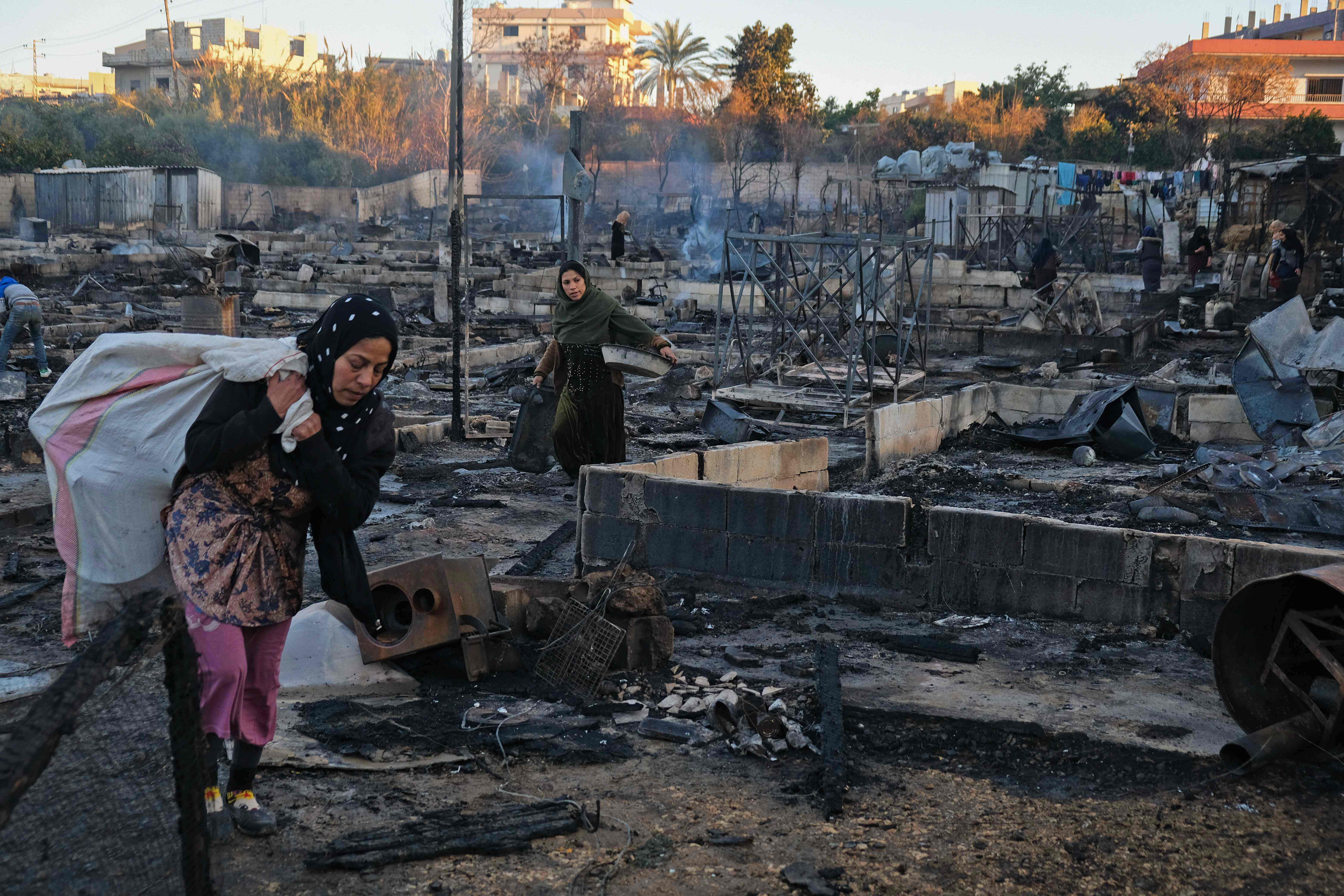 Syrian refugees salvage belongings from the wreckage of their shelters at a camp set on fire overnight in the northern Lebanese town of Bhanine. Credit: AFP Photo