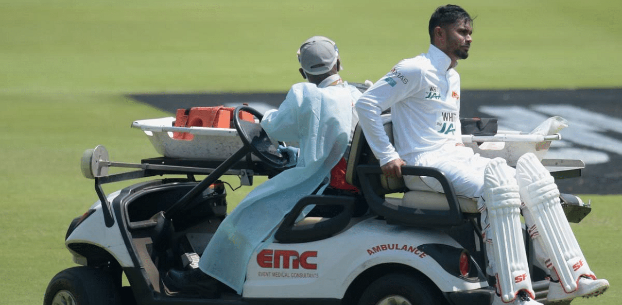 Sri Lanka's Dhananjaya de Silva (R) is helped off the field by medical staff after being injured during the first day of the first Test. Credit: AFP Photo