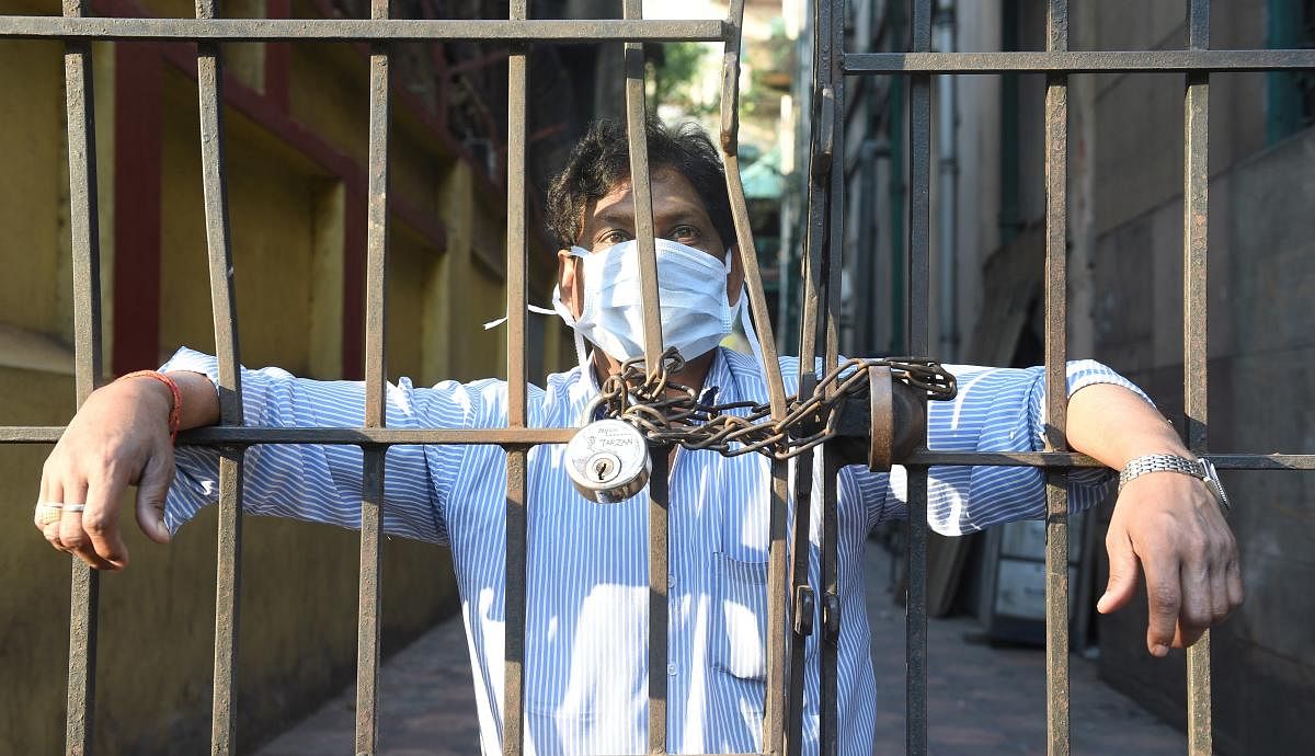   Kolkata: A man, wearing a mask, looks from a closed gate during lockdown in the wake of coronavirus pandemic, in Kolkata , Tuesday, March 24, 2020. Credit: PTI File Photo