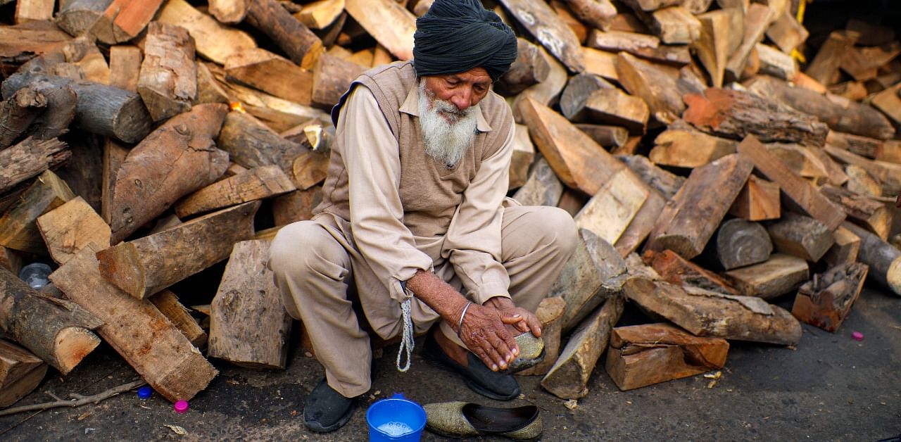 A Sikh farmer clean his shoes during the protest against farm laws, at Singhu border, in New Delhi. Credit: PTI Photo