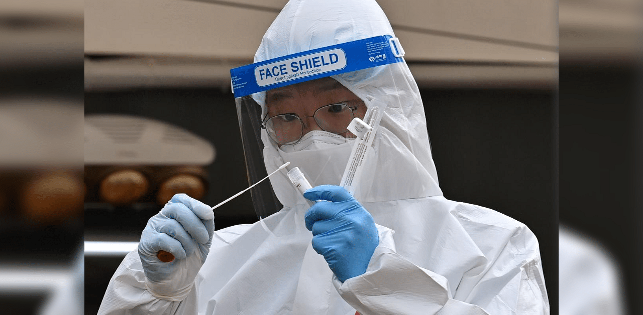 A medical staff member wearing protective gear takes a swab from a visitor to test for the Covid-19 coronavirus at a temporary testing station outside the City Hall in Seoul on December 28, 2020. Credit: AFP Photo