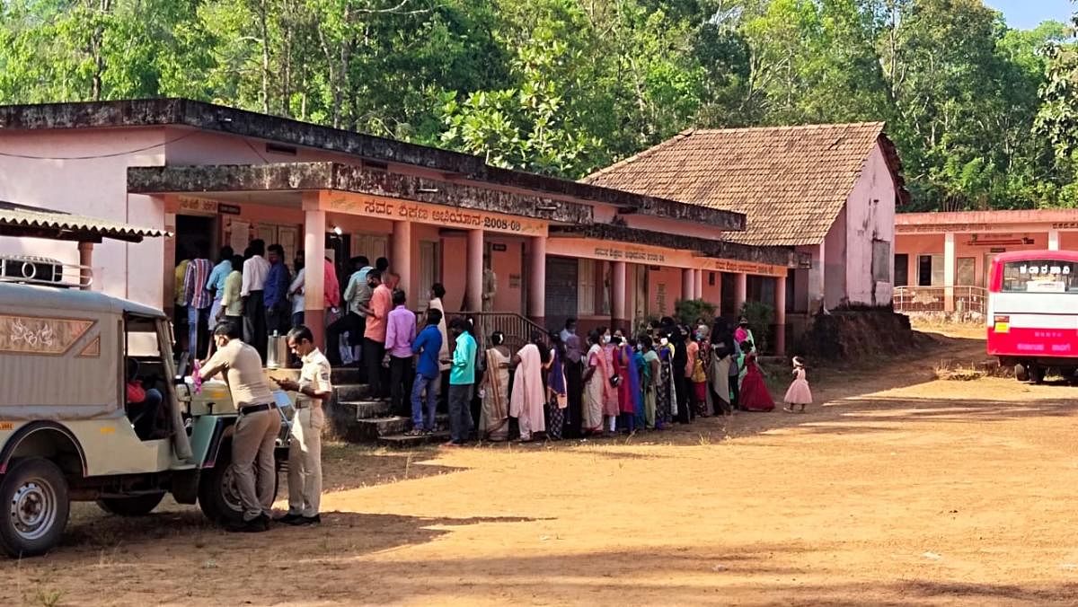 Voters standing in a queue at a booth in Kuthloor. Credit: DH Photo