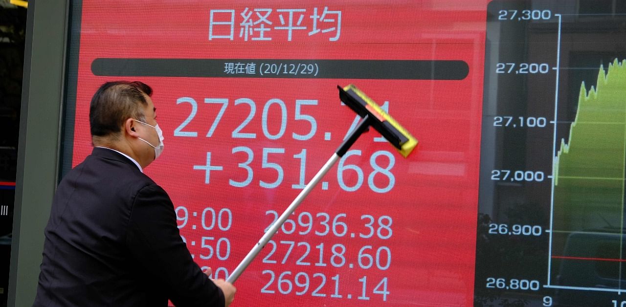 An employee of a securities company cleans an electronic board displaying share prices of the Tokyo Stock Exchange in Tokyo on December on December 29, 2020. Credit: AFP Photo