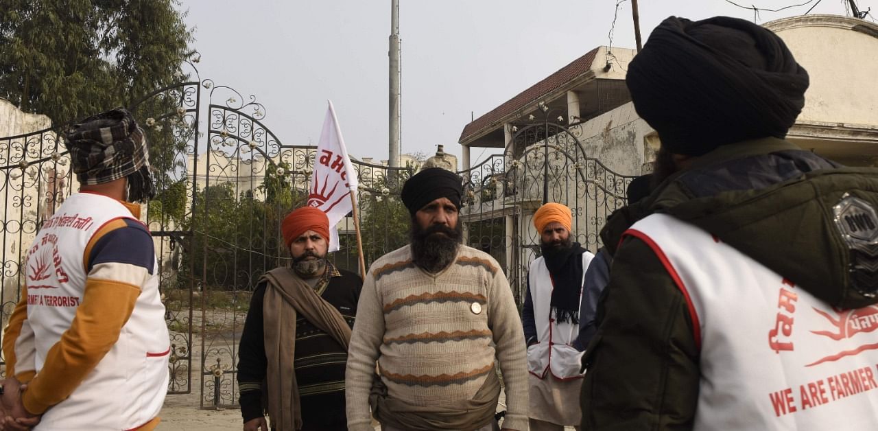 This photo taken on December 28, 2020 shows farmers standing near telecom towers of Reliance Jio during a demonstration against the telecommunications corporation and the central government's recent agricultural reforms, on the outskirts of Amritsar. Credit: AFP Photo