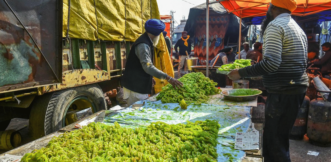 Farmers prepare green colour 'Jalebis', symbolizing green revolution, during their protest against the new farm laws at Singhu border. Credit: PTI Photo