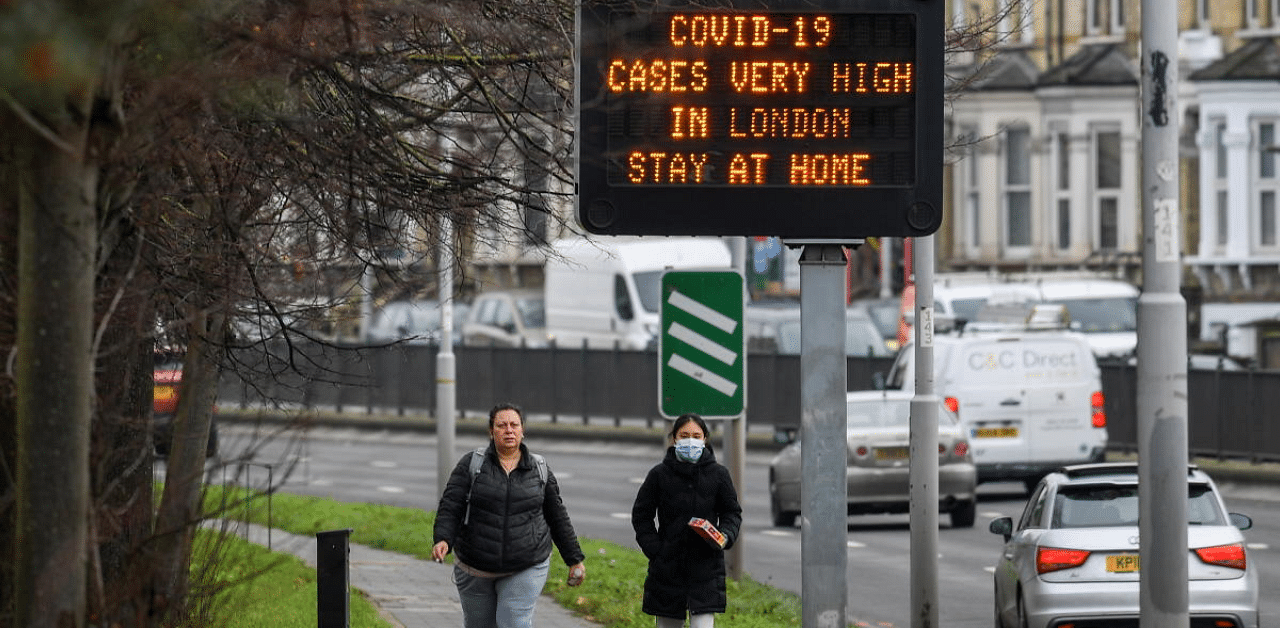 People walk past a roadside public health information sign, amidst the coronavirus disease (Covid-19) pandemic, in London. Credit: Reuters Photo