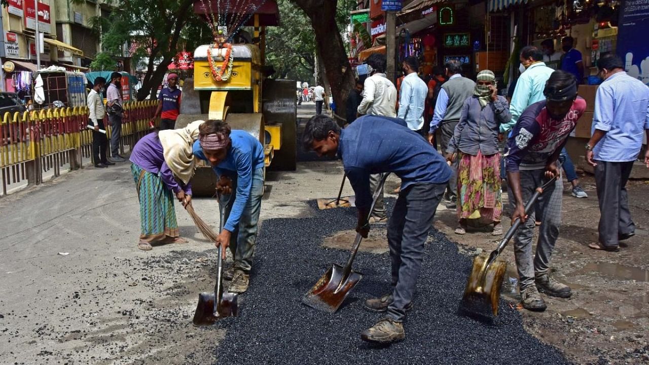 Workers fill up potholes on BVK Iyengar Road in Bengaluru's Chickpete area. Credit: DH Photo