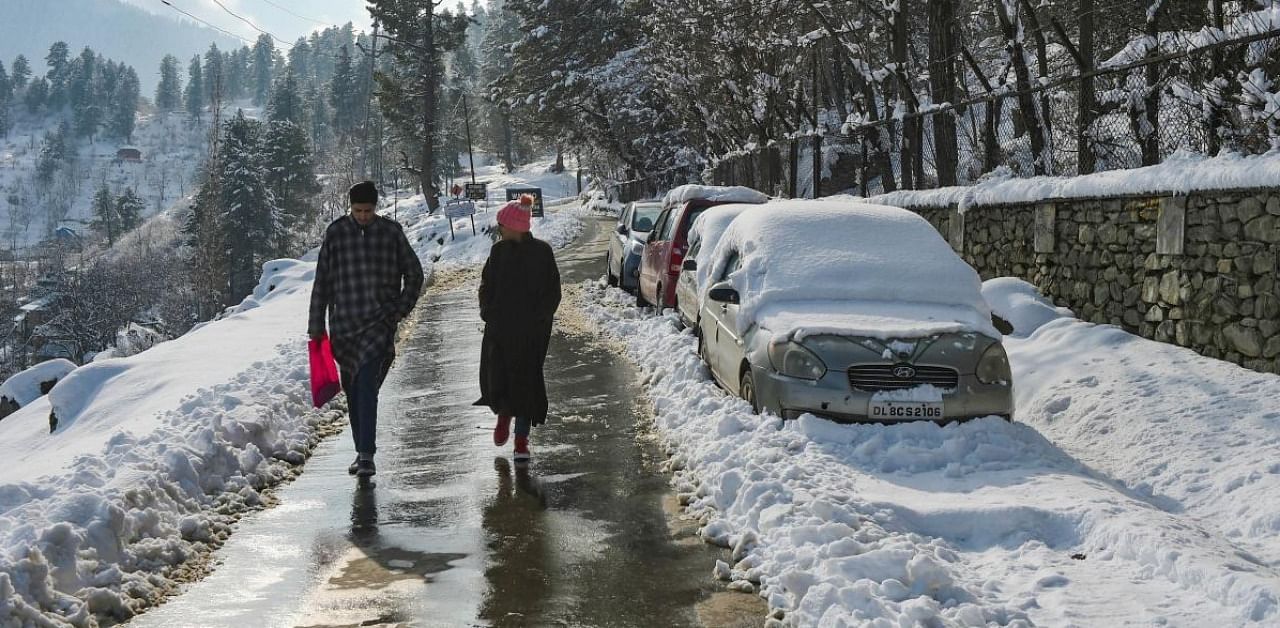 People walk down a road after fresh snowfall at Tangmarg in Baramulla District of north Kashmir. Credit: PTI.