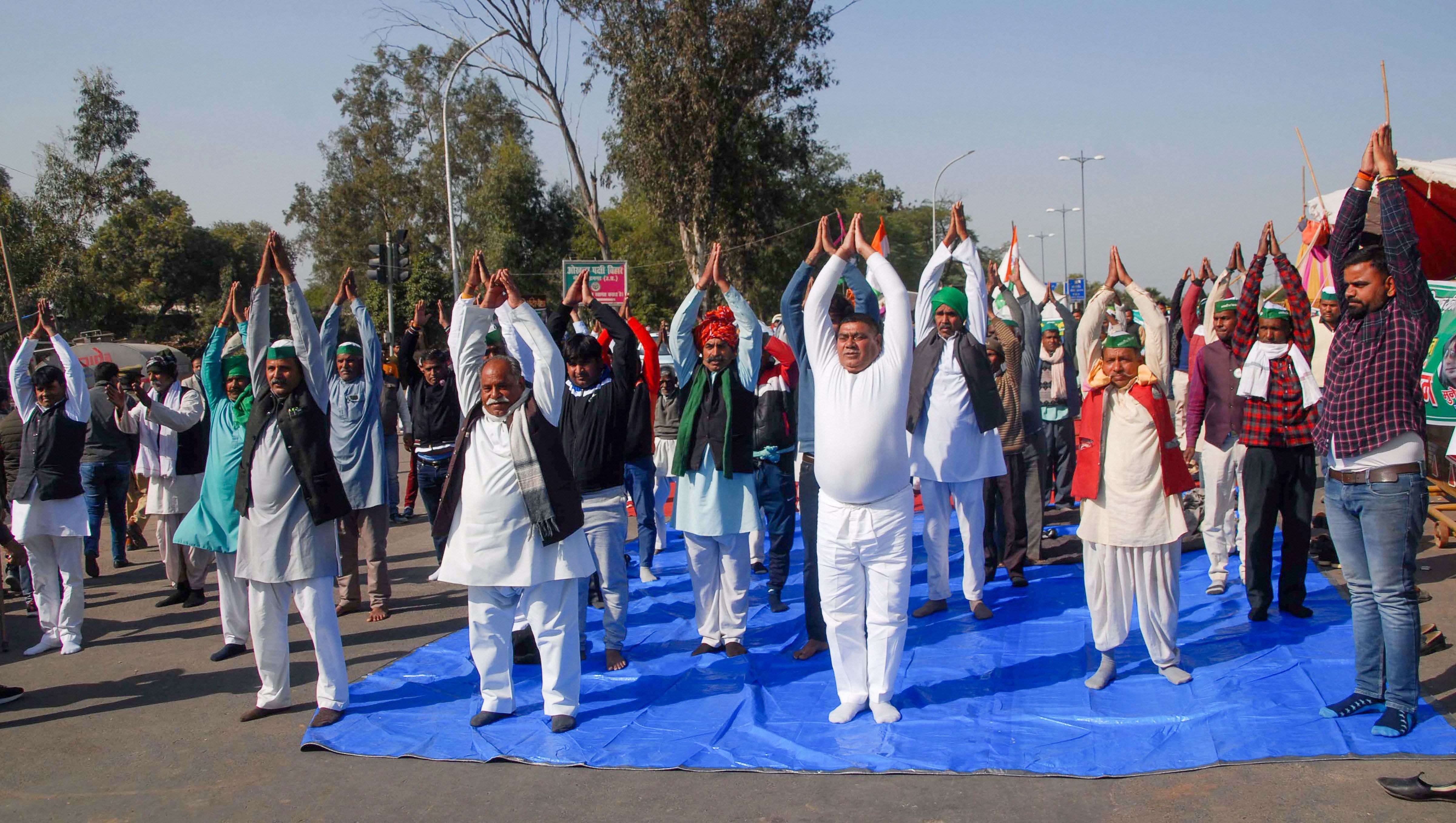 Farmers perform 'yoga' during their ongoing protest against new farm laws, at Noida-Delhi border. Credit: PTI Photo
