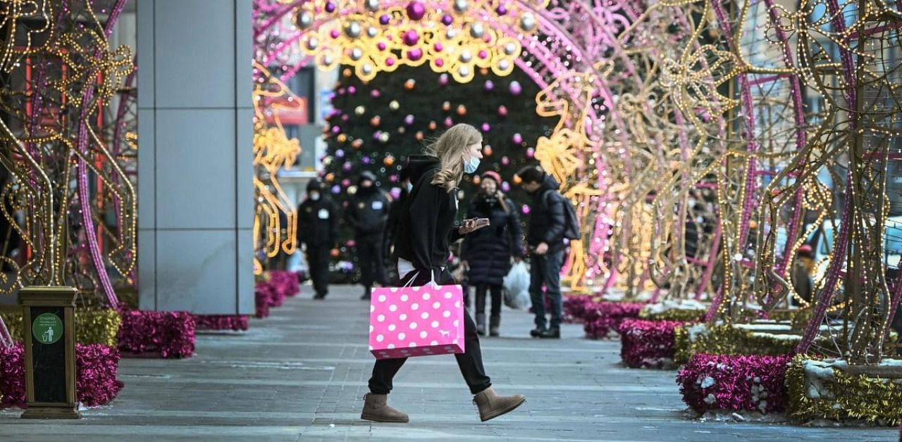 A pedestrian wearing a face mask walks under Christmas decorations in front of a shopping mall in Moscow. Credit: AFP.