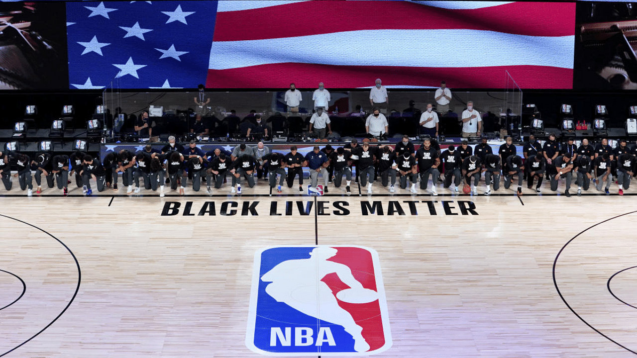Members of the New Orleans Pelicans and Utah Jazz kneel together around the Black Lives Matter logo on the court during the national anthem before the start of an NBA basketball game. Credit: AFP File Photo