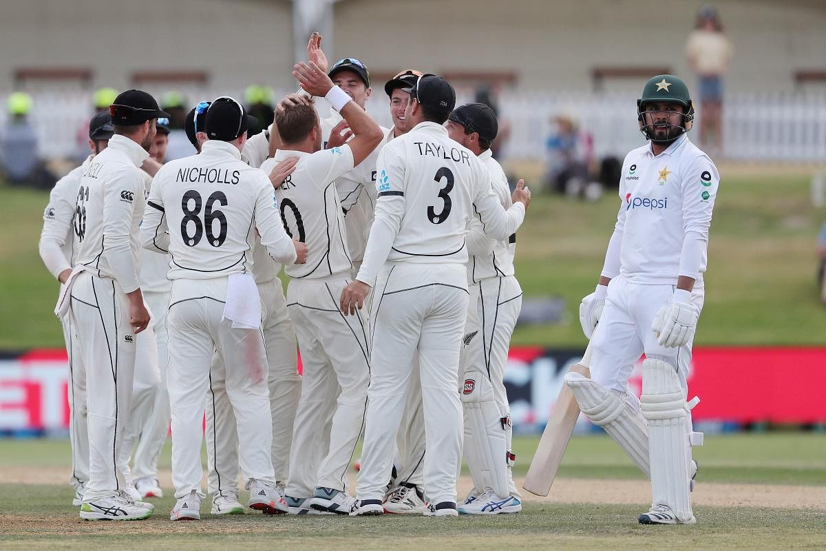 New Zealand (L) celebrate after taking the wicket of Pakistan’s Faheem Ashraf (R) during the fifth day of the first cricket Test match between New Zealand and Pakistan at the Bay Oval in Mount Maunganui. Credit: AFP. 