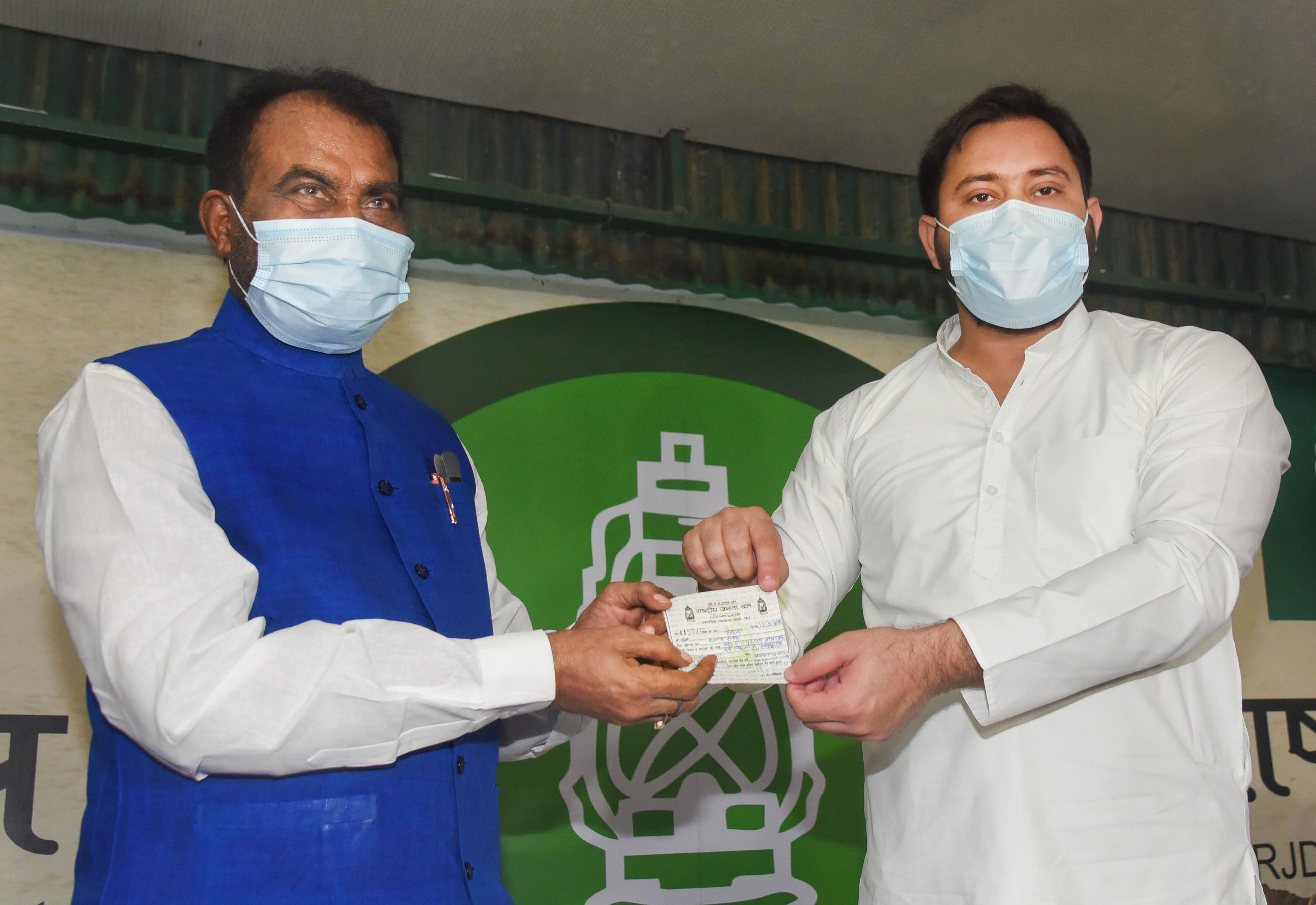 RJD leader Tejaswi Yadav presents the membership slip to former cabinet minister and former JD-U leader Shyam Rajak as he joins RJD party, in Patna, Monday, Aug. 17, 2020. Credit: PTI Photo