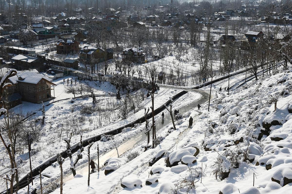 People walk on a road after fresh snowfall at Tangmarg in Baramulla District of north Kashmir, Tuesday, Dec. 29, 2020. The fresh snowfall in parts of Jammu and Kashmir has led to the closure of Srinagar-Jammu National Highway. Credit: PTI Photo