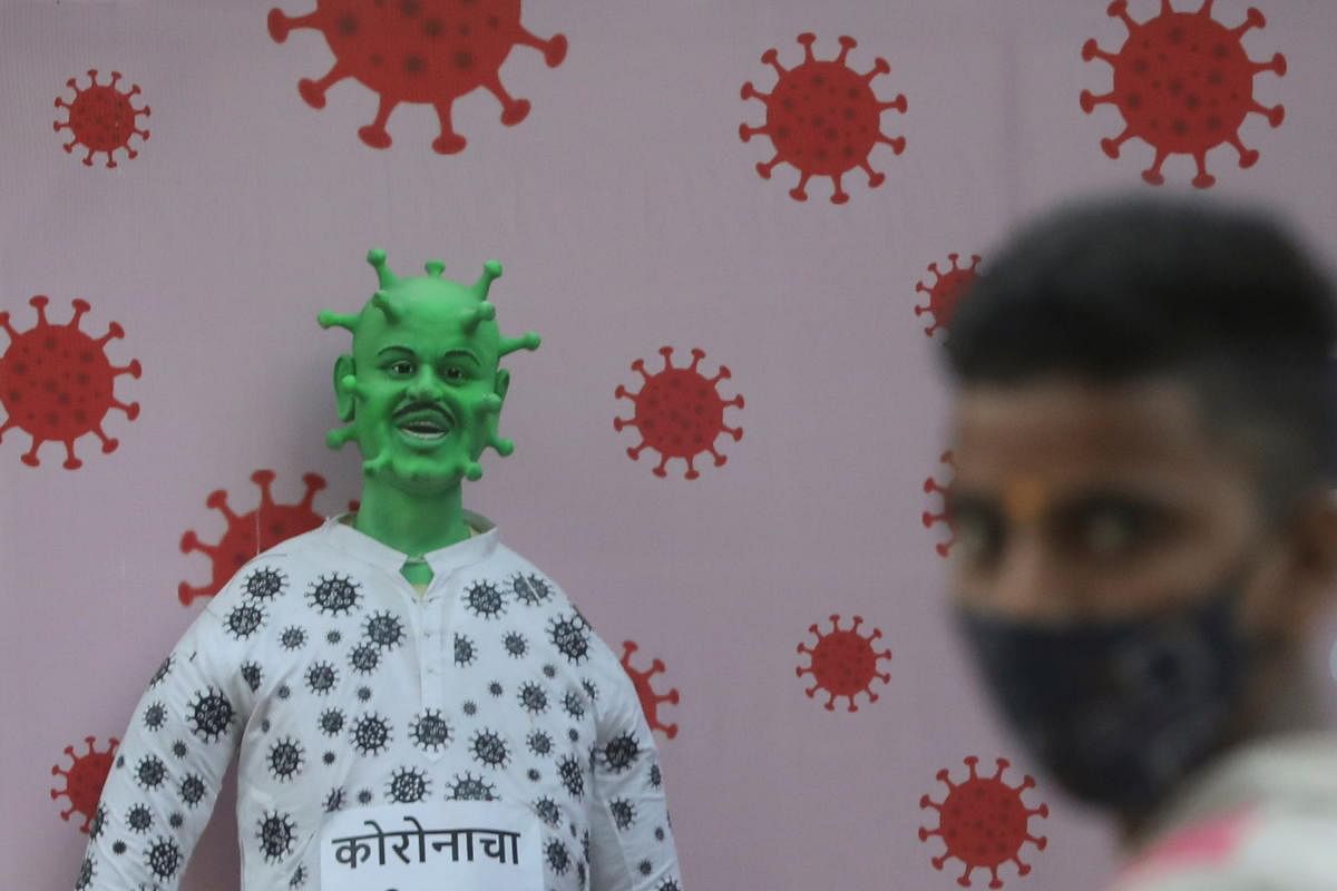 A man is seen in front of an dummy representing the coronavirus disease (COVID-19) outside a housing society in Mumbai, India. Credit: Reuters. 