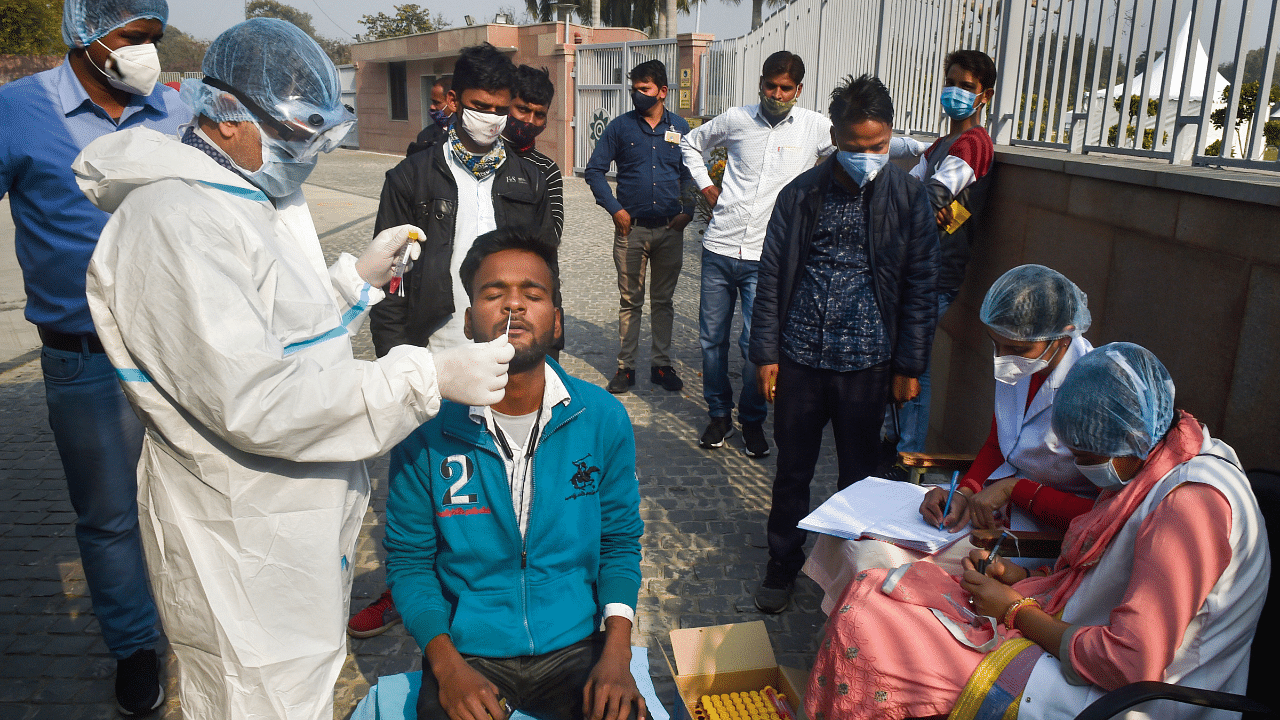 A health worker wearing PPE kit collects samples for the Covid-19 test. Credit: PTI Photo