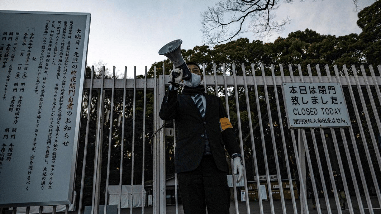 A shrine staff member uses a megaphone to announce the early closing time for Meiji Shrine on New Year's Eve in Tokyo. Credit: AFP