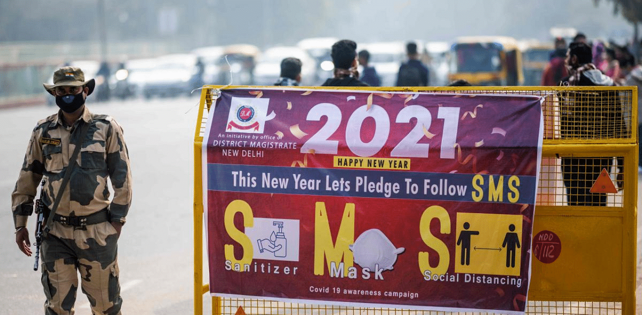 A security personnel walks past a sign displayed on a police barricade near India Gate on New Year's Eve in New Delhi. Credit: AFP Photo