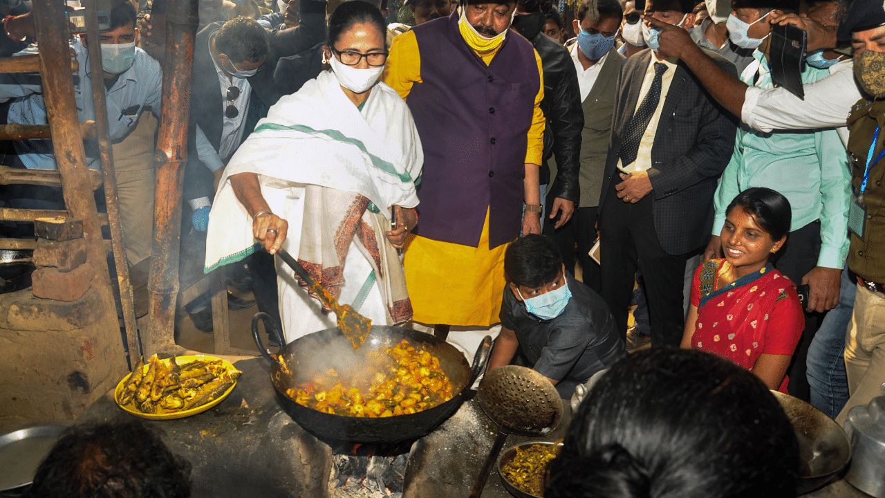 West Bengal Chief Minister Mamata Banerjee tries her hand at cooking on a chullha as she visits a tribal village at Shantiniketan in Birbhum district. Credit: PTI Photo