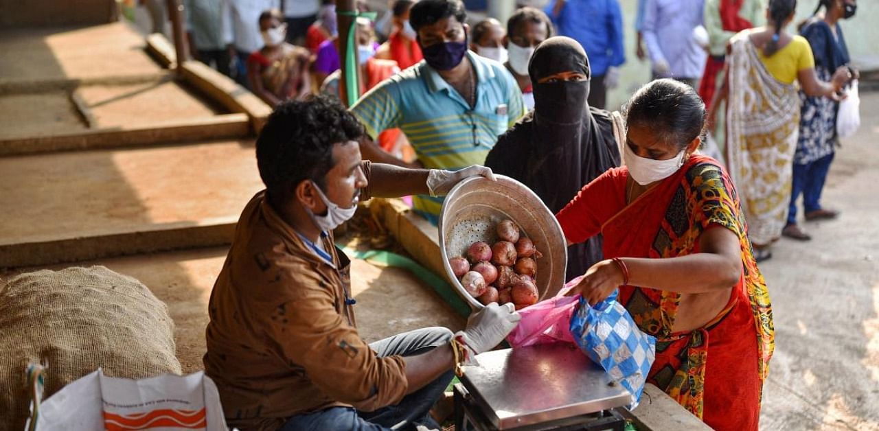 People buy onions at a vegetable market in Vijayawada. Credit: PTI.