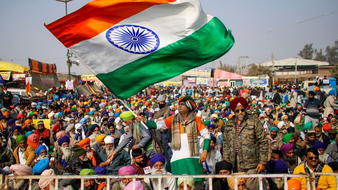 A farmer holds the Tricolor during a protest against the new farm laws, at Singhu Border in New Delhi. Credit: PTI Photo