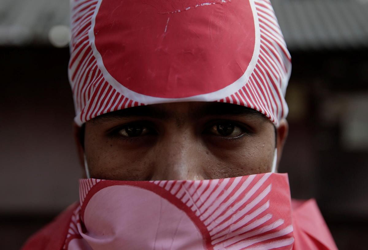 A protester affiliated with a faction of the ruling Nepal Communist Party has his face covered with the party flag during a rally against the dissolution of parliament, in Kathmandu, Nepal December 29, 2020. Credit: REUTERS