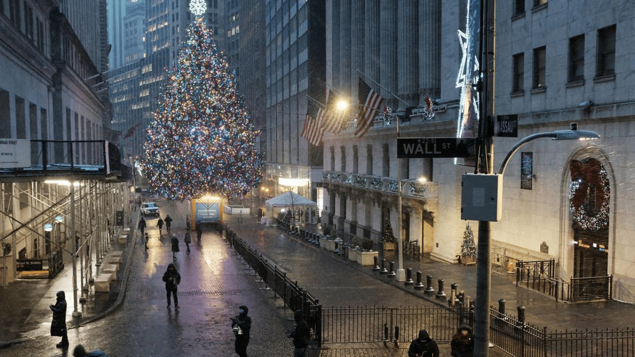 People walk through the blowing snow along Wall Street in New York City, United States. Credit: AFP File Photo