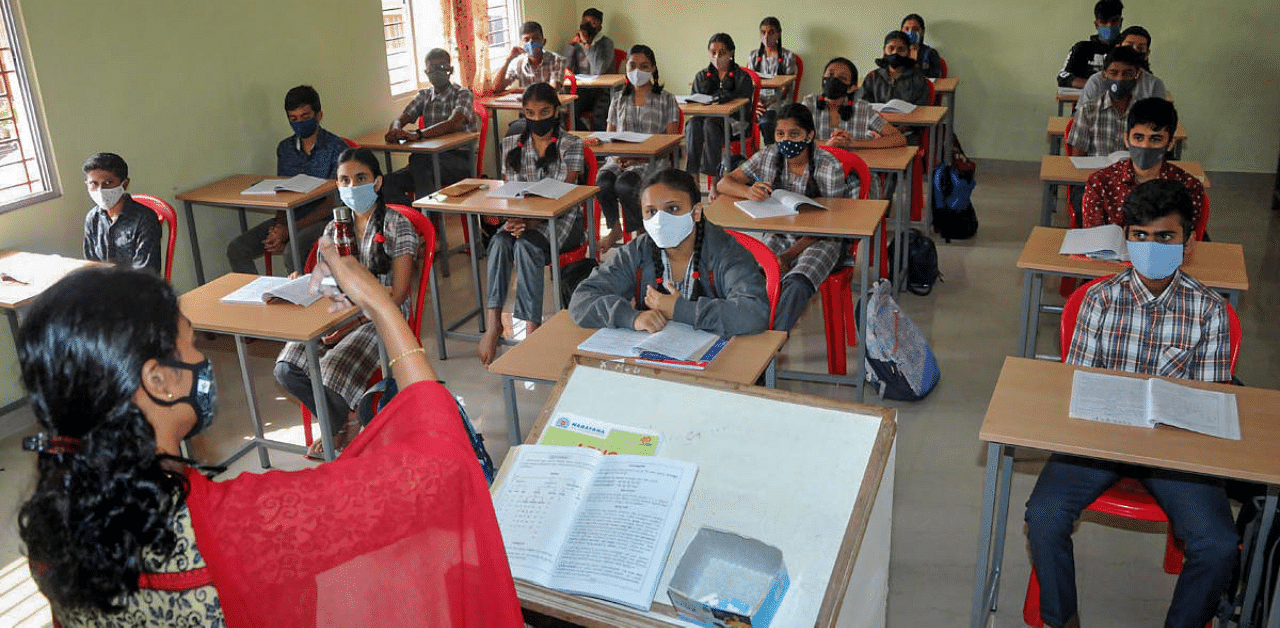 Students of the 10th class, wearing masks, attend a class at a school that was reopened after remaining closed for months due to Covid-19 pandemic, in Chikmagalur, Karnataka. Credit: PTI Photo