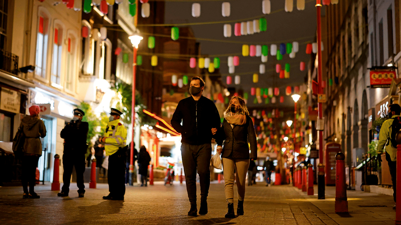 A couple wearing protective face coverings to combat the spread of the coronavirus, walk through China Town in central London on New Year's Eve. Credit: AFP Photo