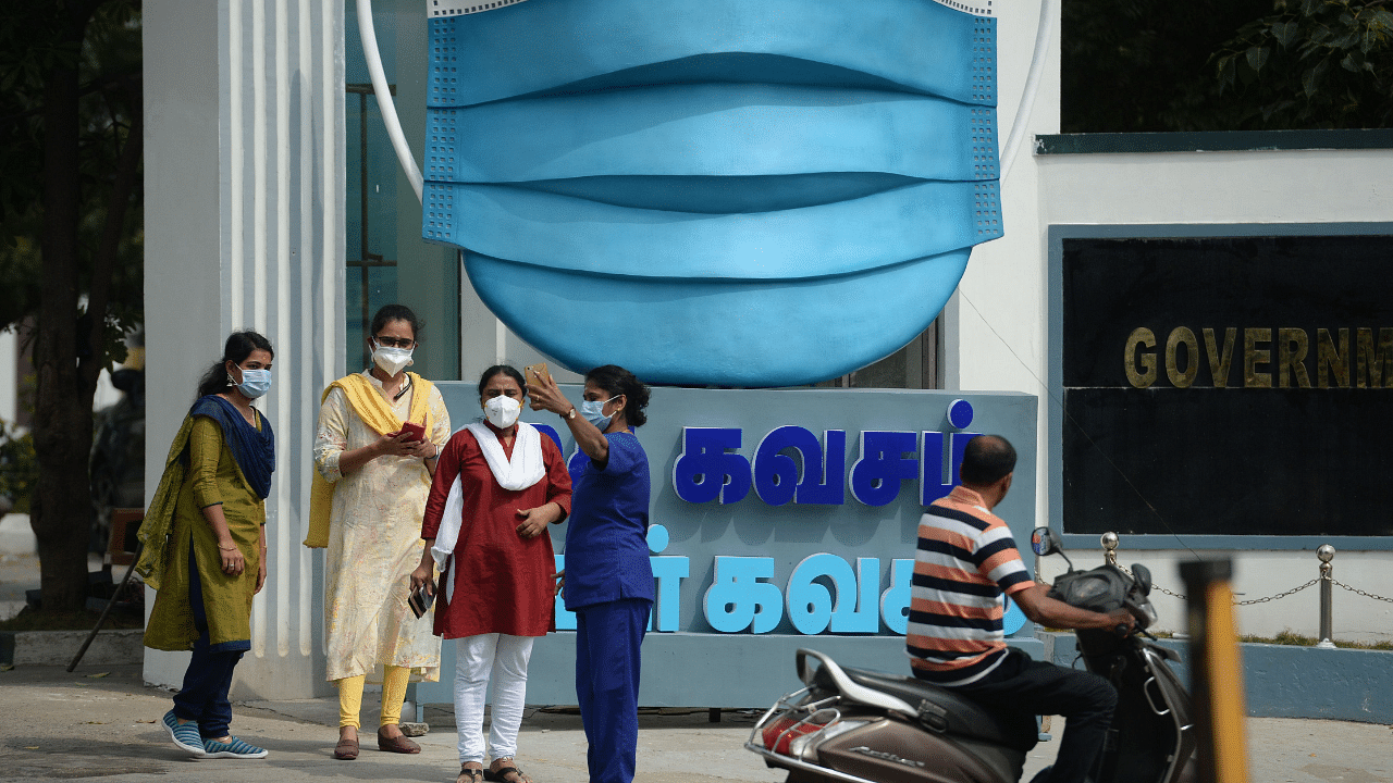 Medical staff take pictures beside a large replica facemask displayed as an awareness campaign against the Covid-19. Credit: AFP Photo