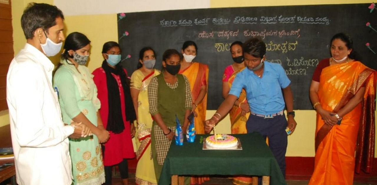 A student cuts cake to celebrate the reopening of the Government High School, at Police Colony in Mandya. Credit: Special arrangement.