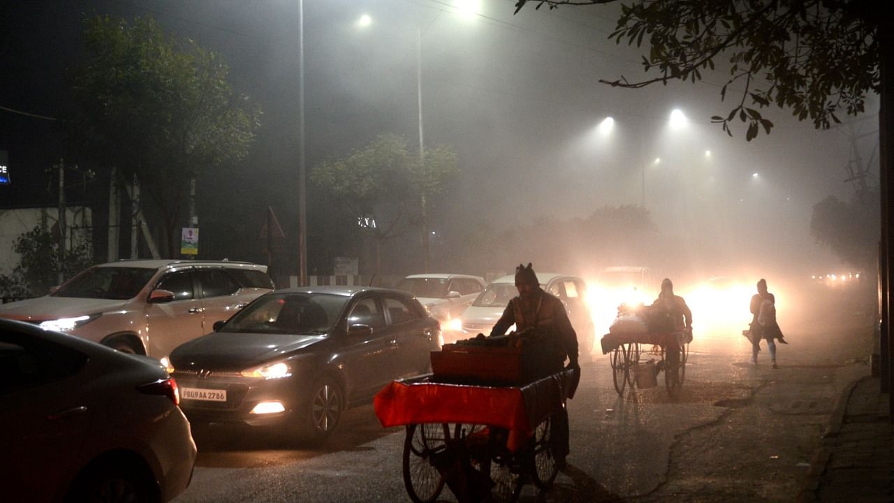Vehicles ply on road amid dense fog, in Jalandhar. Credit: PTI Photo