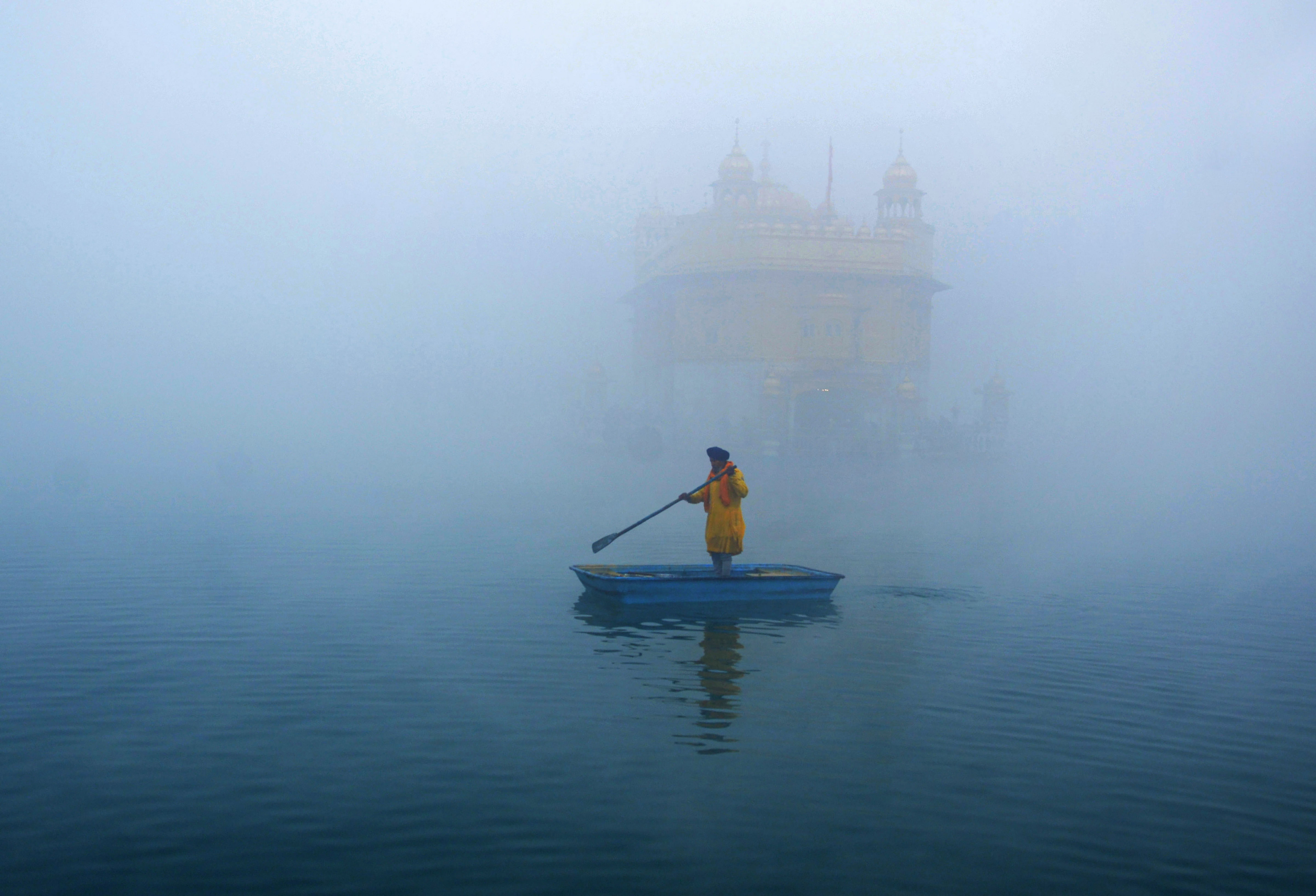A 'sewadar' cleans the sacred pond at the Golden Temple amid fog, on New Year's Day, in Amritsar, Friday, Jan. 1, 2021. Credit: PTI Photo