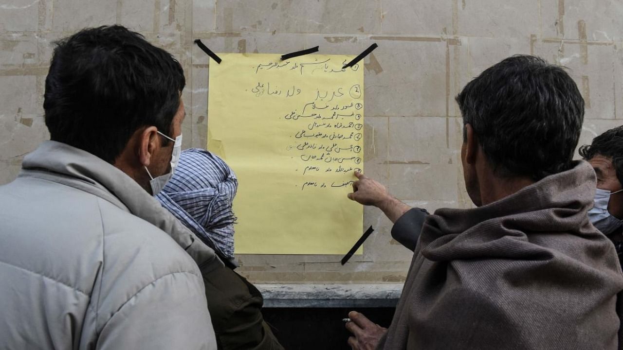 Members of Shiite Hazara community check a list of victims after the killing of 11 workers of their community, in Quetta. Credit: AFP.