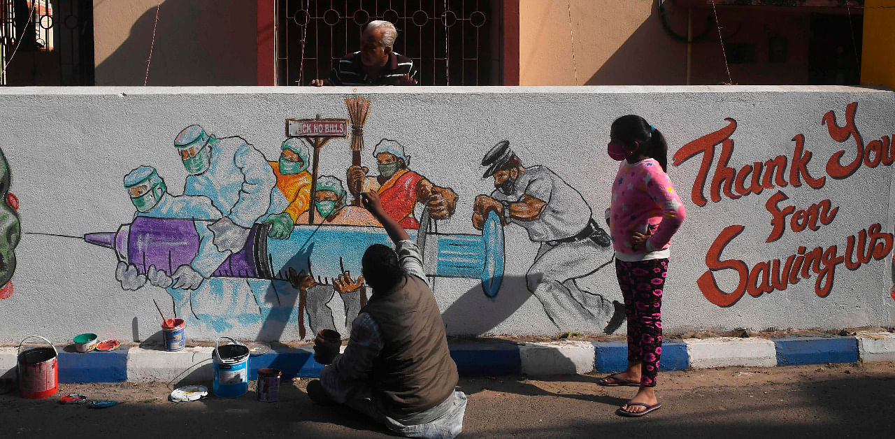 An artist gives finishing touches to a mural depicting frontline workers carrying a Covid-19 coronavirus vaccine in Kolkata. Credit: AFP Photo