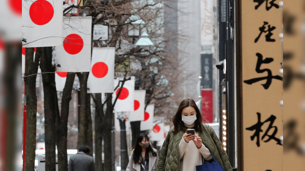 Pedestrians wearing protective masks, following the coronavirus disease (COVID-19) outbreak, walk underneath Japanese national flags at a shopping district in Tokyo, Japan, January 6, 2021. Credit: Reuters Photo