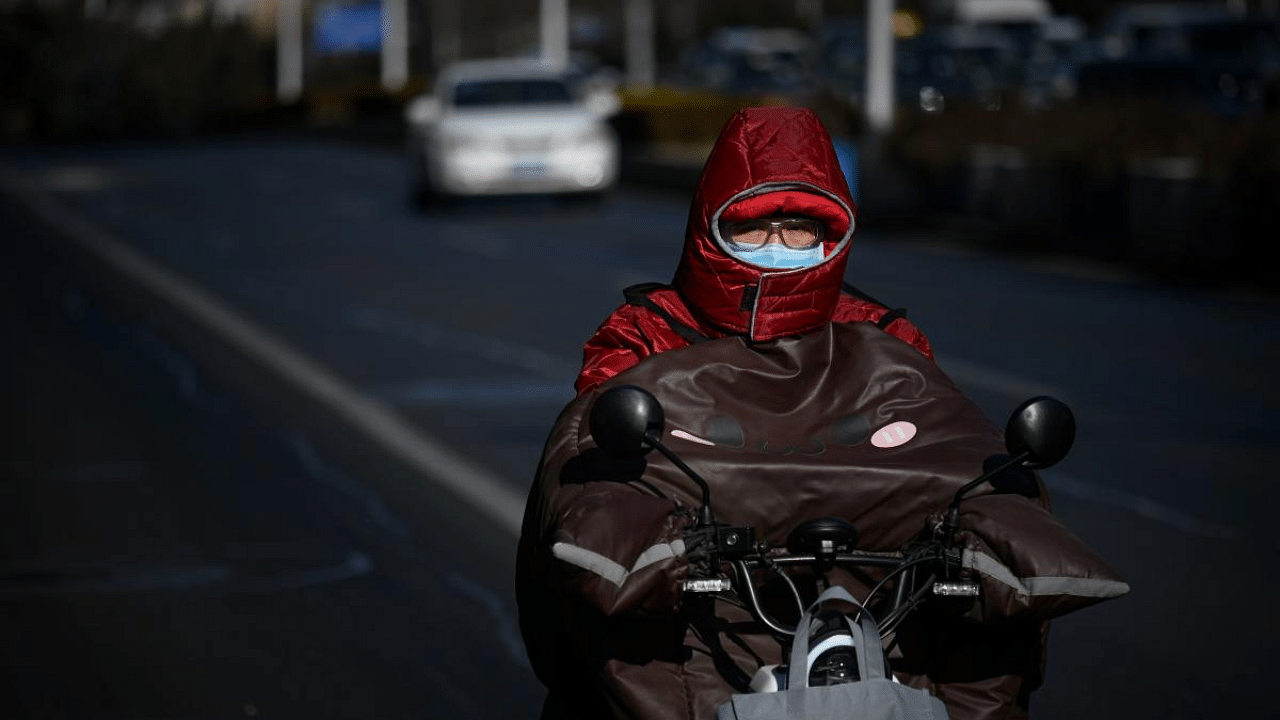 A man wrapped up in the cold rides his motorcycle along a street on a winter day in Beijing after China's meteorological authority recently issued a severe weather warning across large parts of the country. Credit: AFP Photo