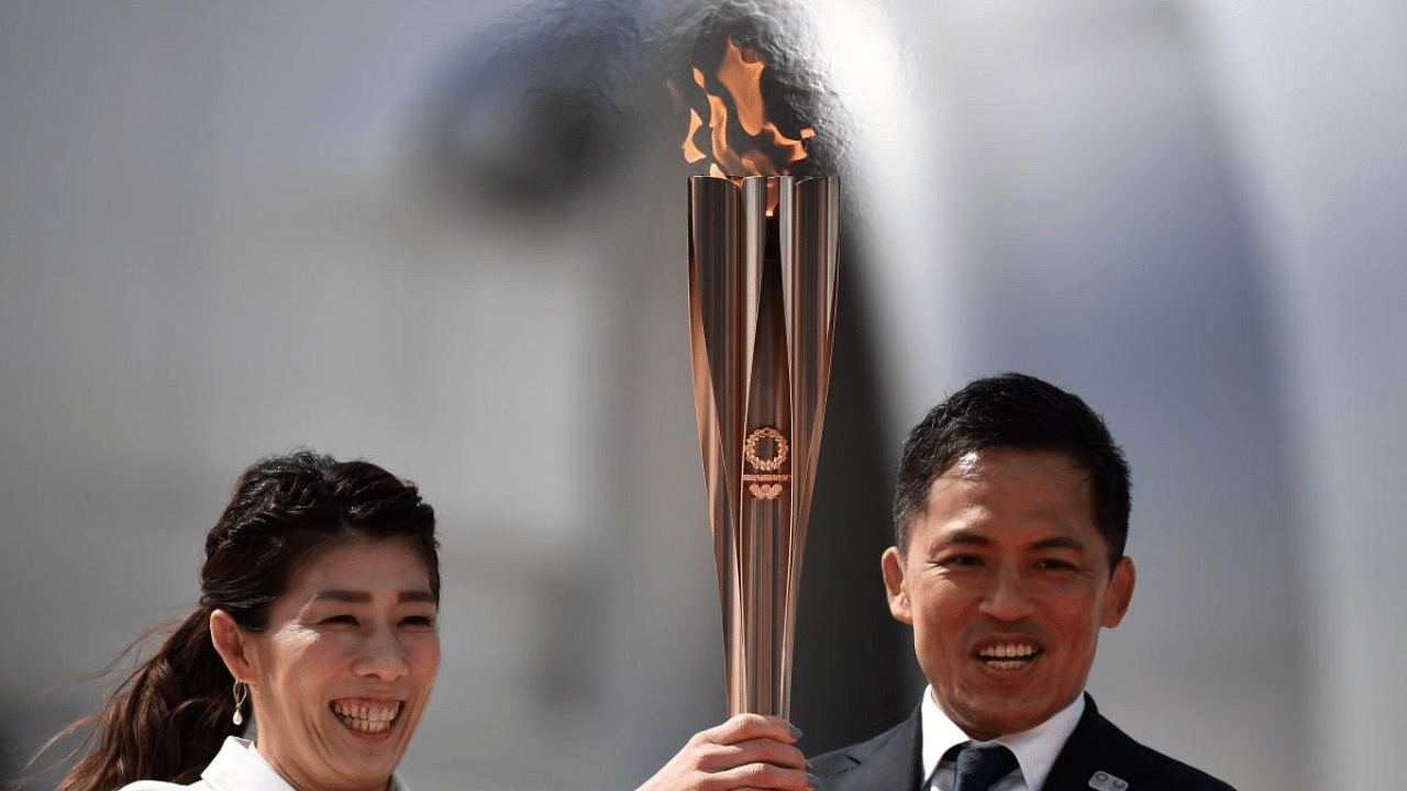 Japanese three-time Olympic gold medallists Saori Yoshida (L) and Tadahiro Nomura (R) hold the Tokyo 2020 olympic torch, after transporting the flame from Greece, at the Japan Air Self-Defense Force Matsushima Base in Higashimatsushima, Miyagi prefecture. Credit: AFP File Photo