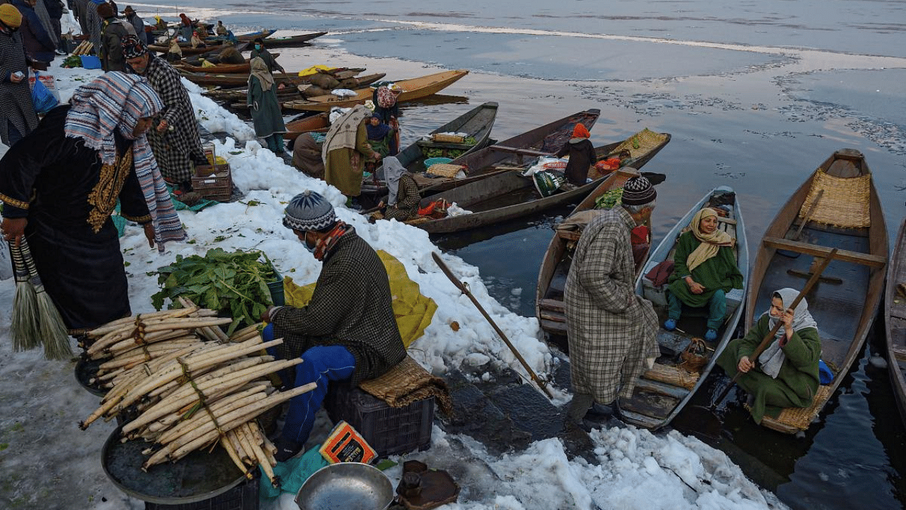 A roadside vendor sells vegetables on the banks of Dal Lake after a recent snowfall, in Srinagar. Credit: PTI File Photo