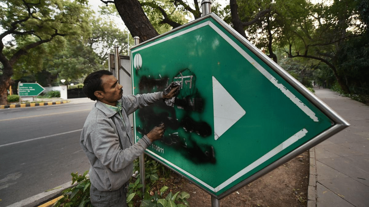 A man cleans the Aurangzeb Lane signboard that was blackened. Credit: PTI File Photo