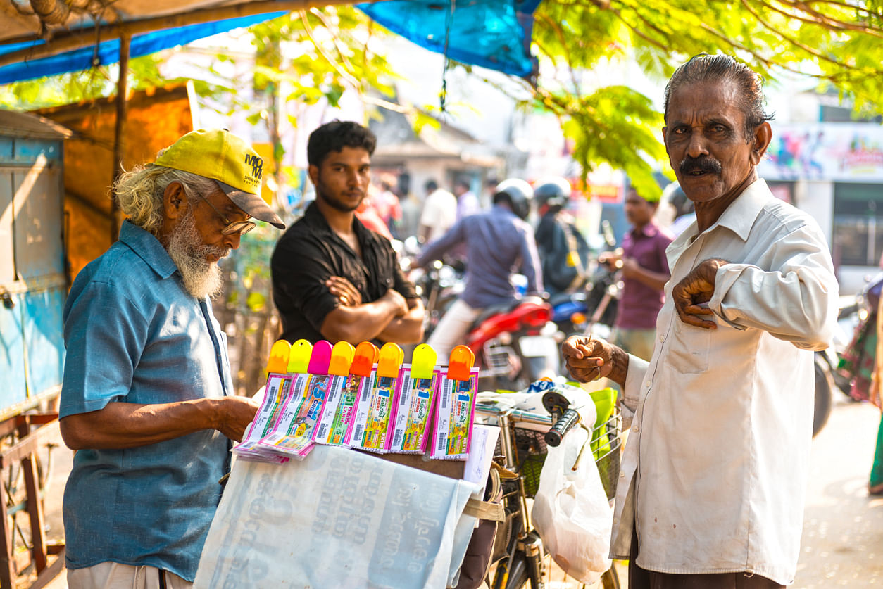 In front stall with colorful lottery tickets and three man standing around it to sell and buy the ticket. Credit: iStock Photo